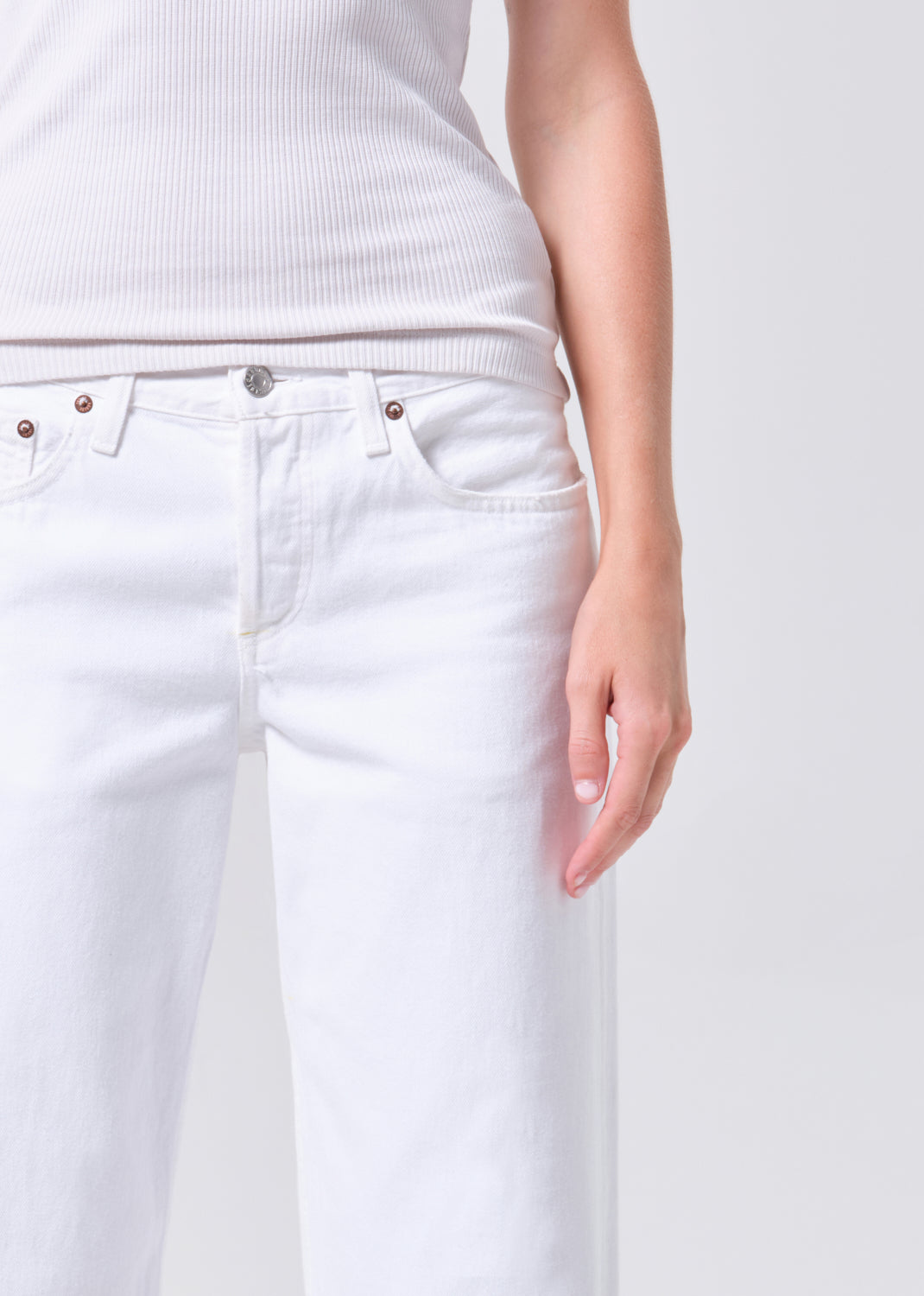 White jeans worn by a person on a plain background