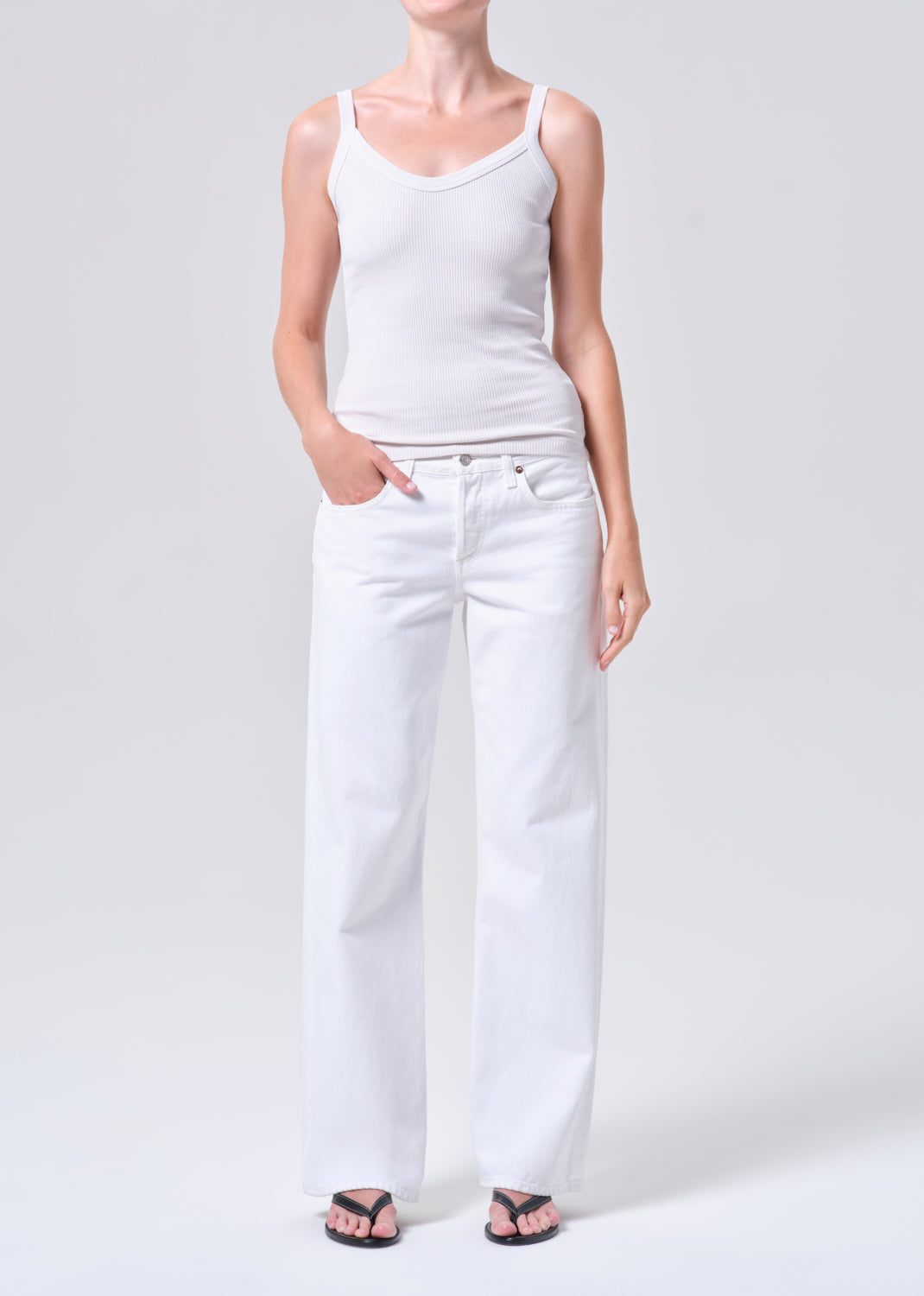 Person wearing a white tank top and white pants on a plain background