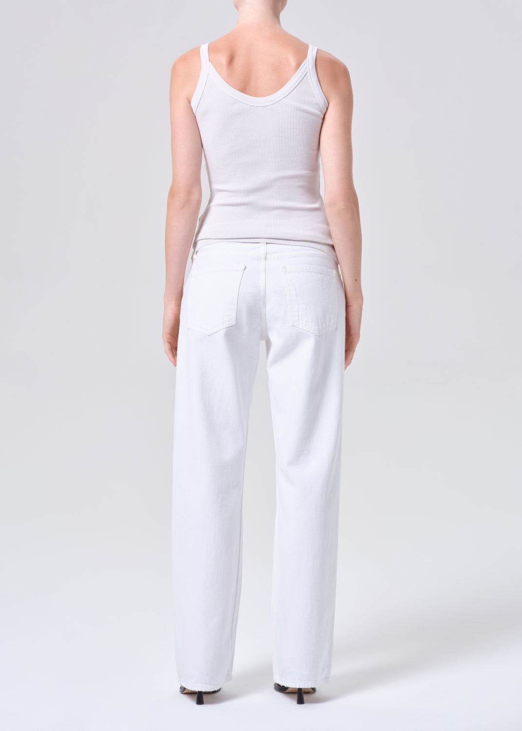 Person wearing a white tank top and pants on a white background