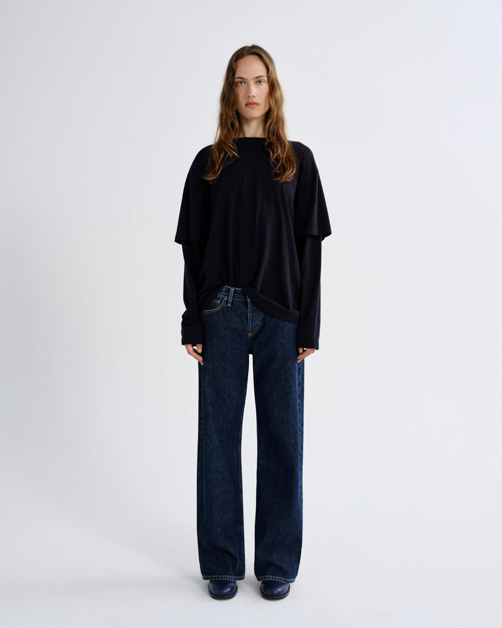 Person wearing a black oversized sweater and dark blue jeans on a white background