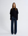 Person wearing a black oversized sweater and dark blue jeans on a white background