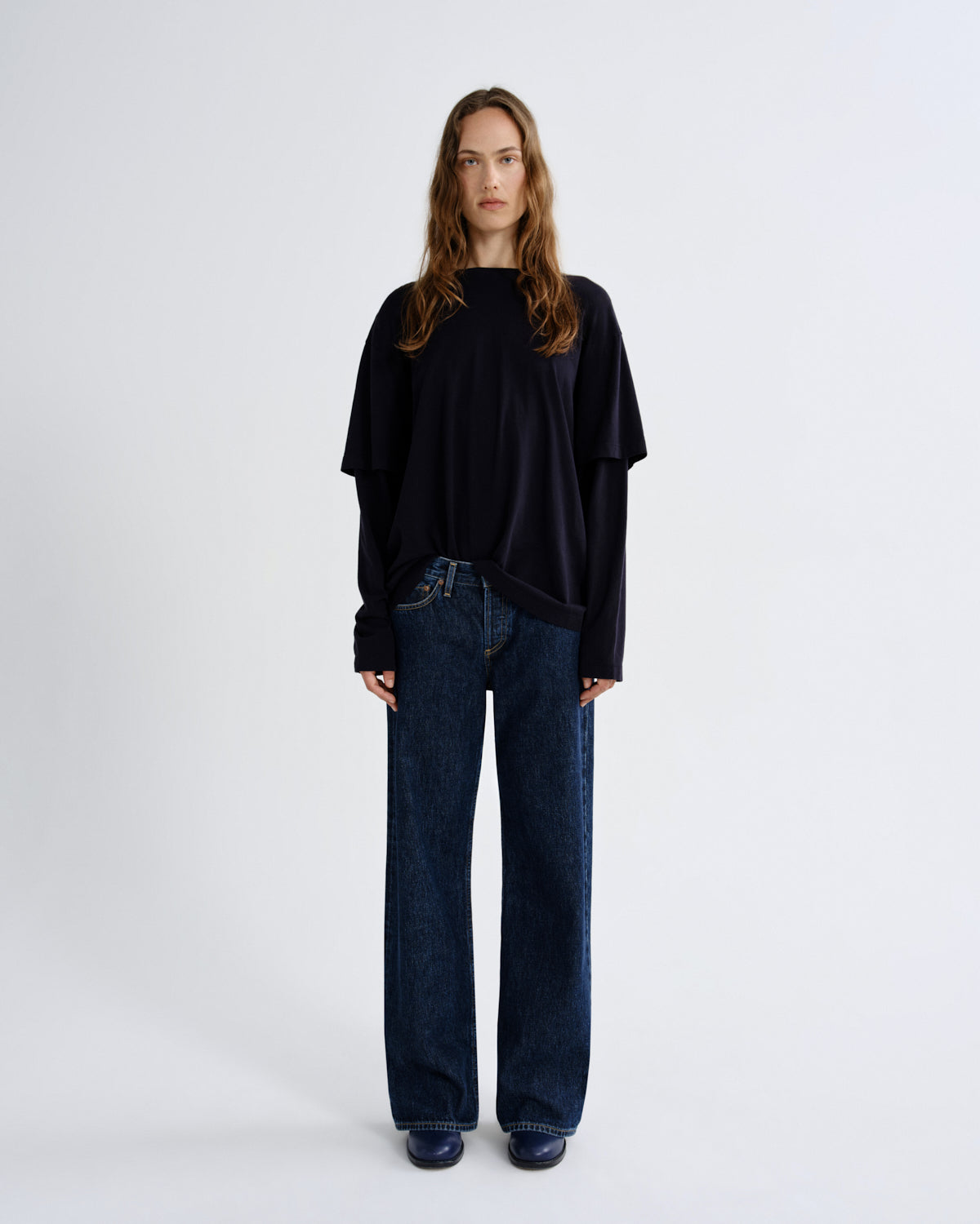 Person wearing a black oversized sweater and dark blue jeans on a white background