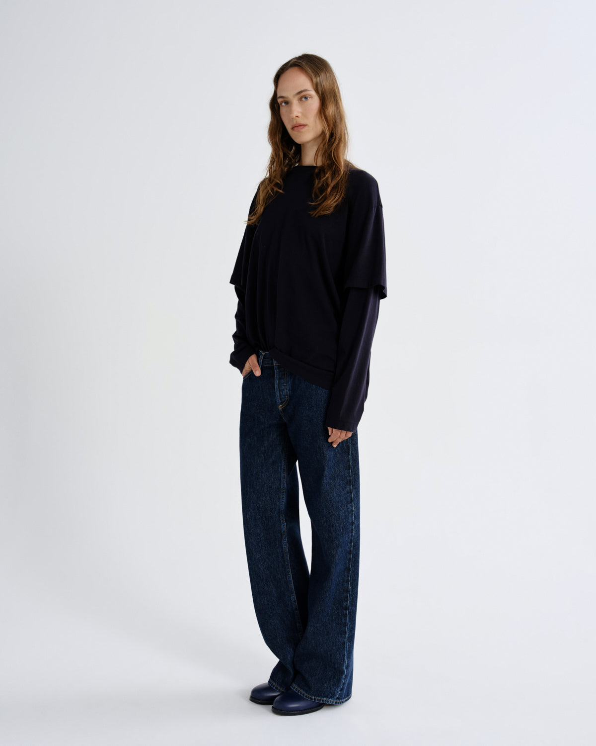 Woman wearing a black sweater and blue jeans on a white background