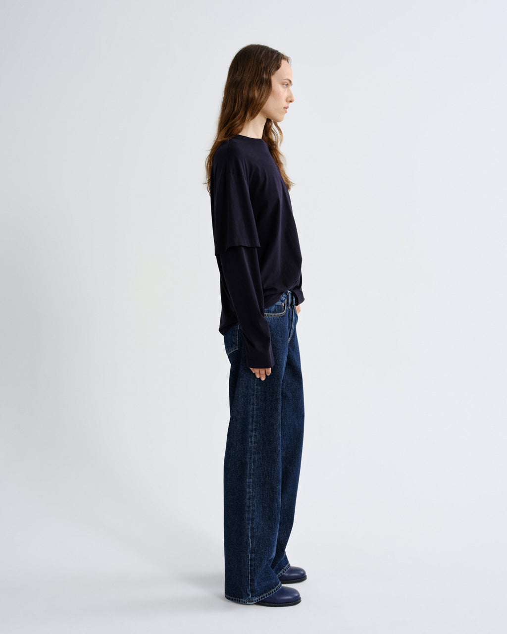 Person wearing a black sweater and blue jeans on a white background
