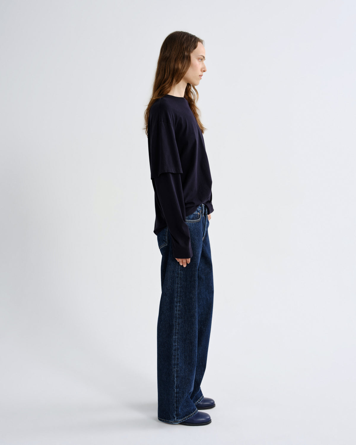Person wearing a black sweater and blue jeans on a white background