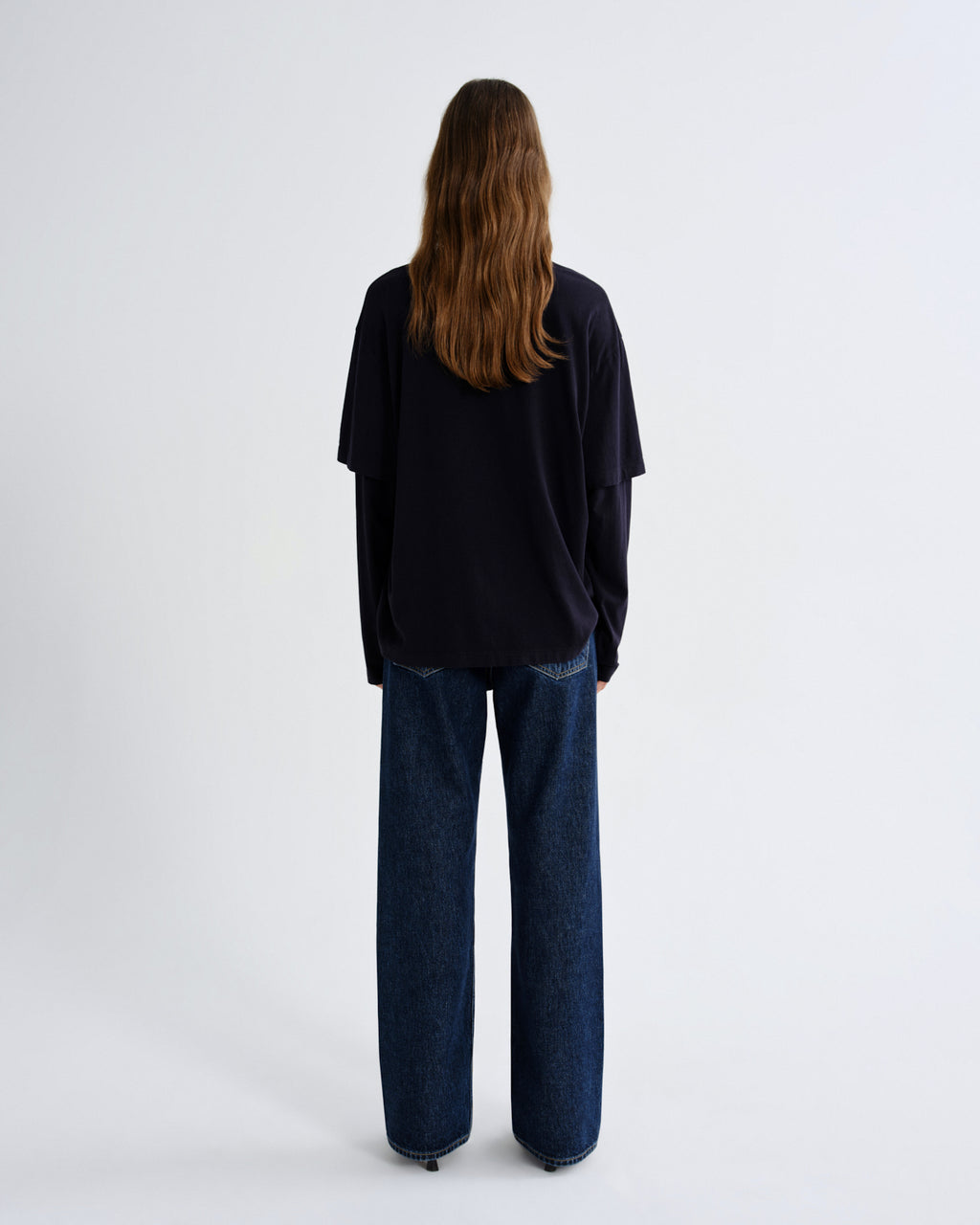 Person wearing a black top and blue jeans on a white background