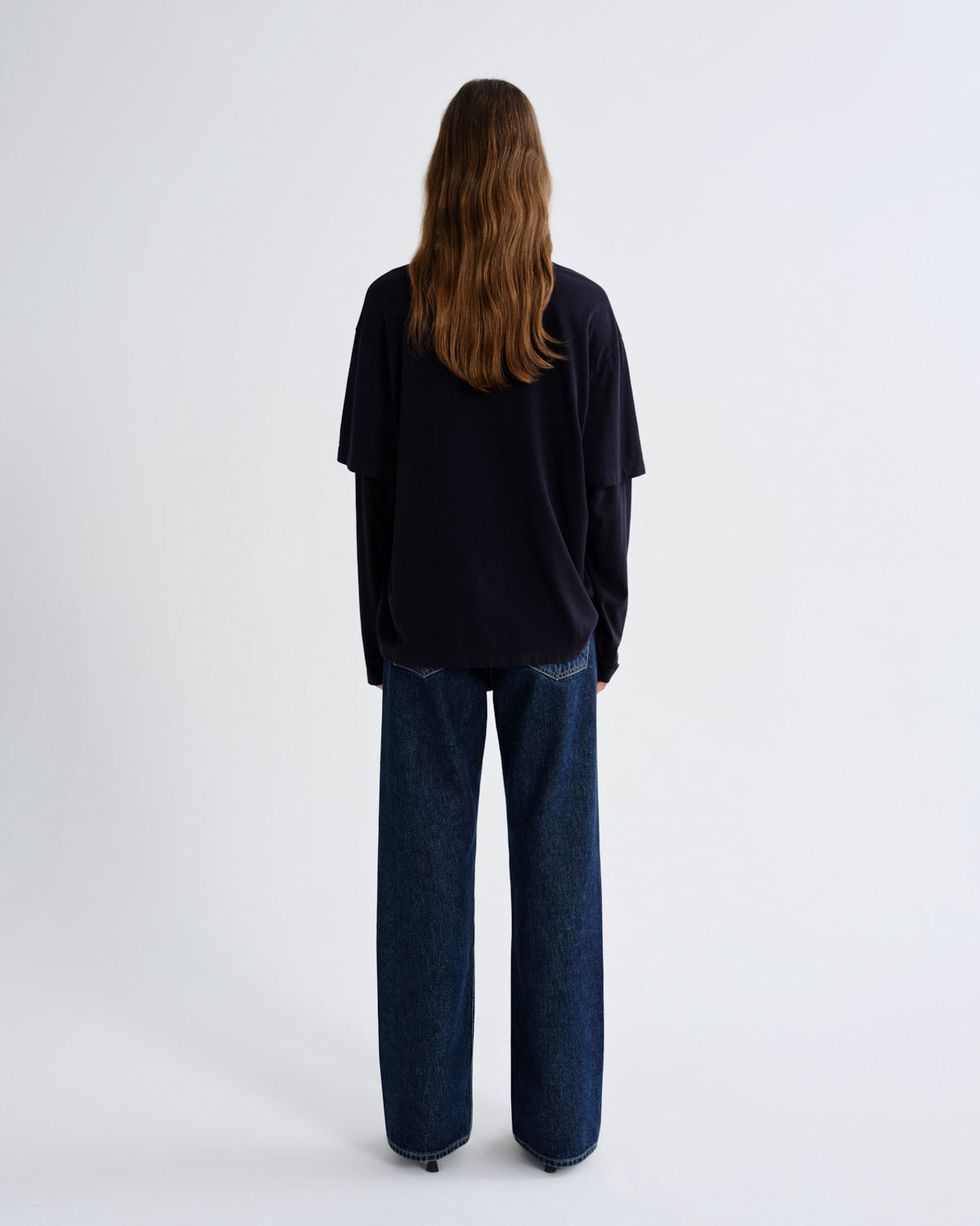 Person wearing a black top and blue jeans on a white background