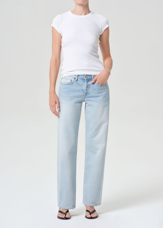 Person wearing light blue jeans and a white t-shirt on a plain background