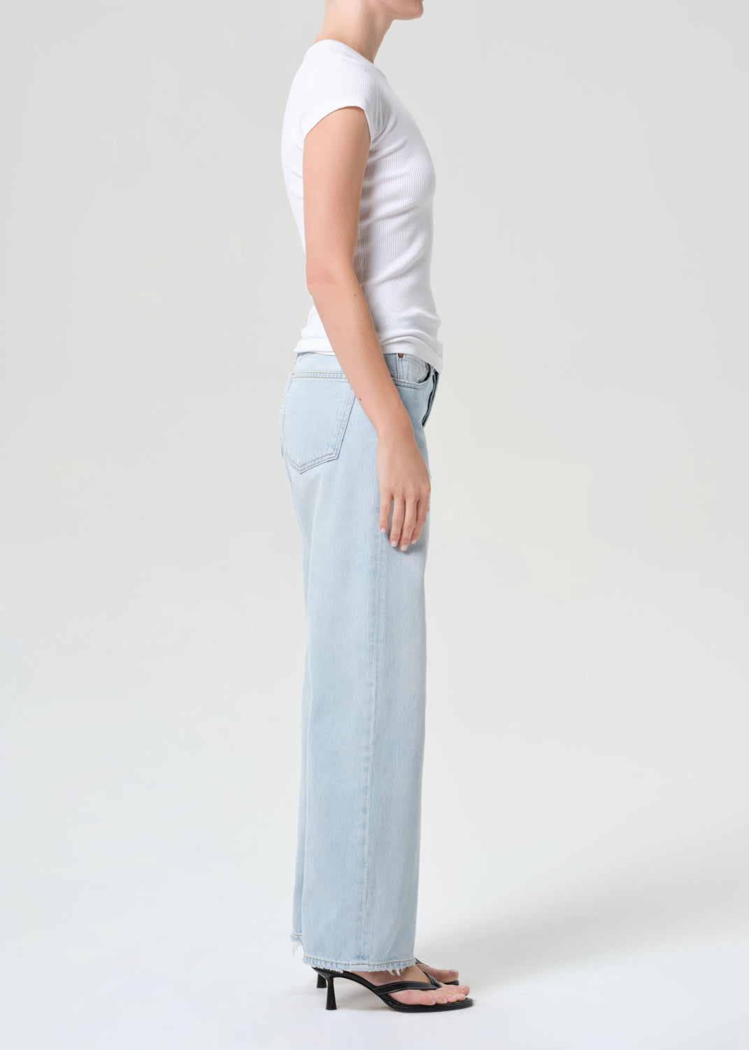 Person wearing a white t-shirt and light blue jeans on a plain background