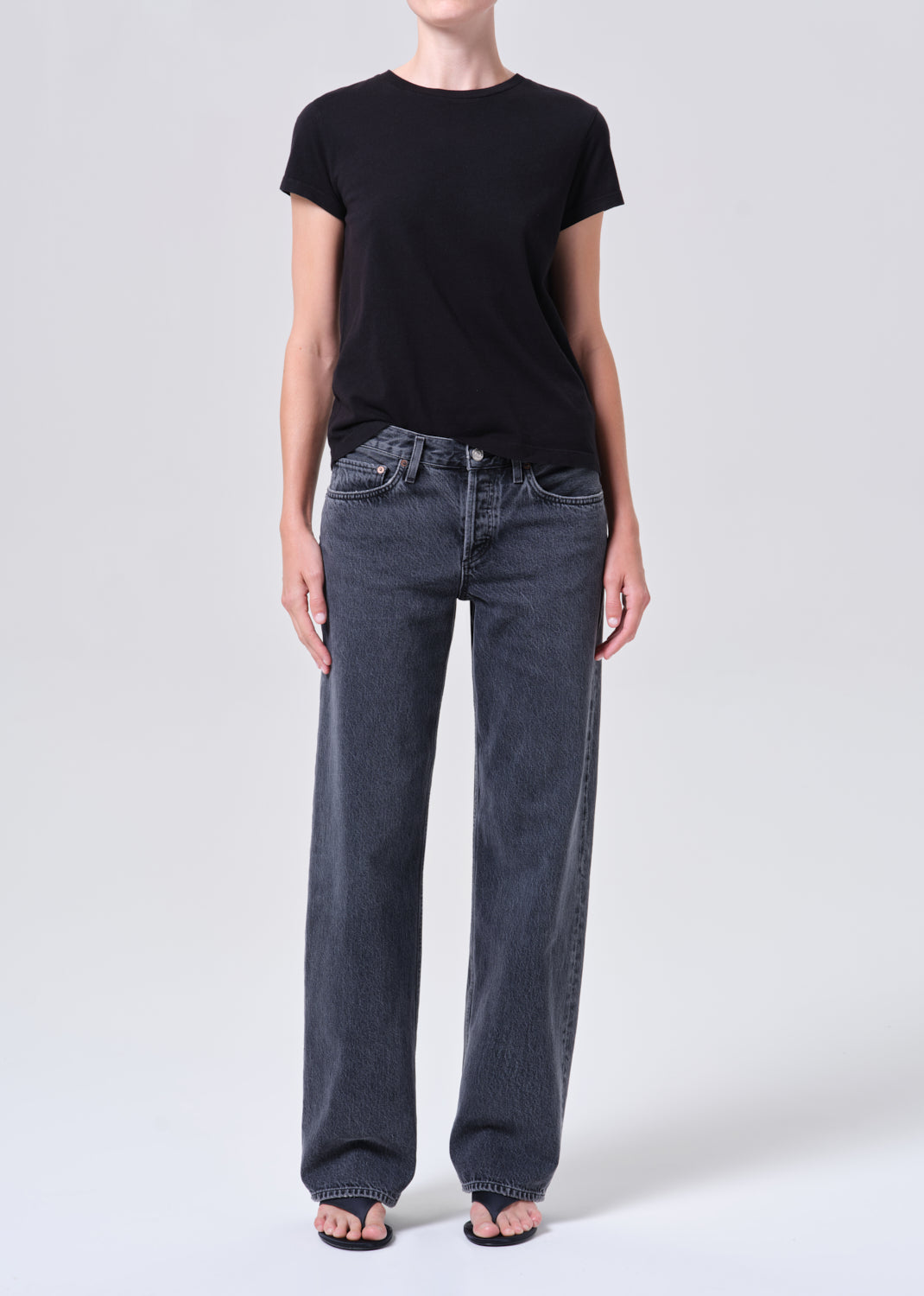 Person wearing a black t-shirt and gray jeans on a white background