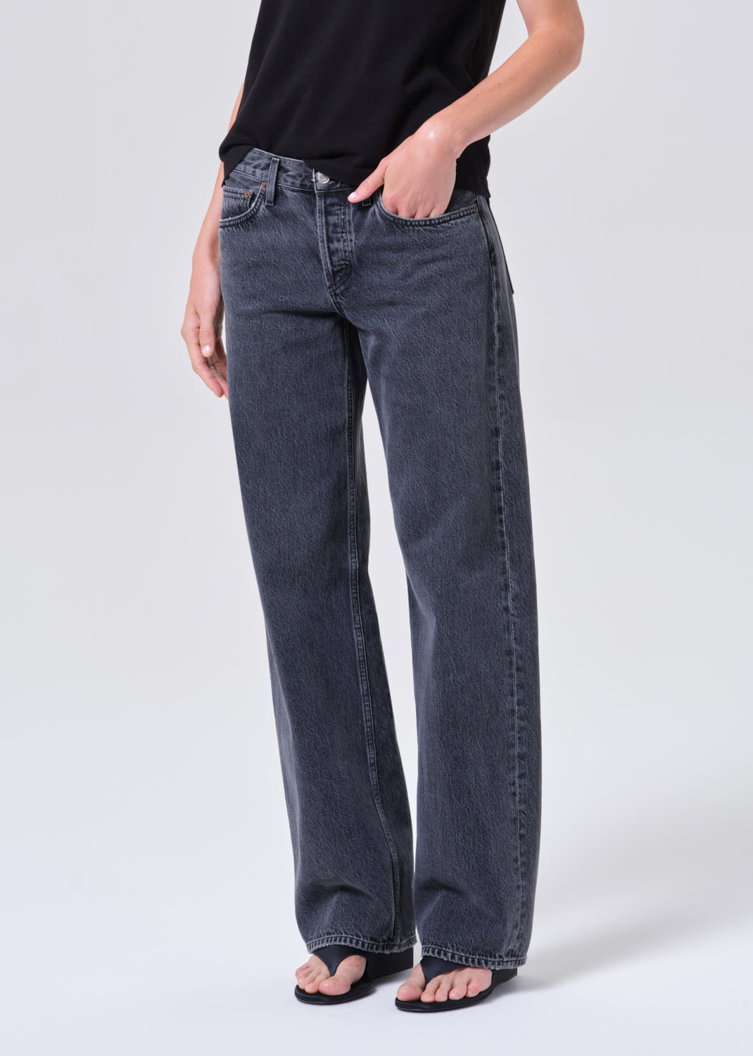 Person wearing dark blue jeans and a black top on a white background