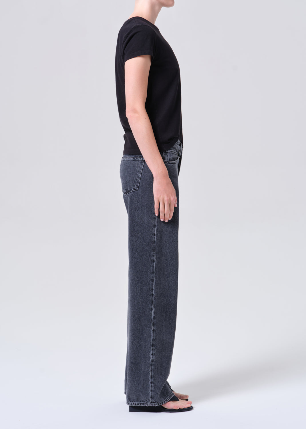 Person wearing a black t-shirt and blue jeans on a white background