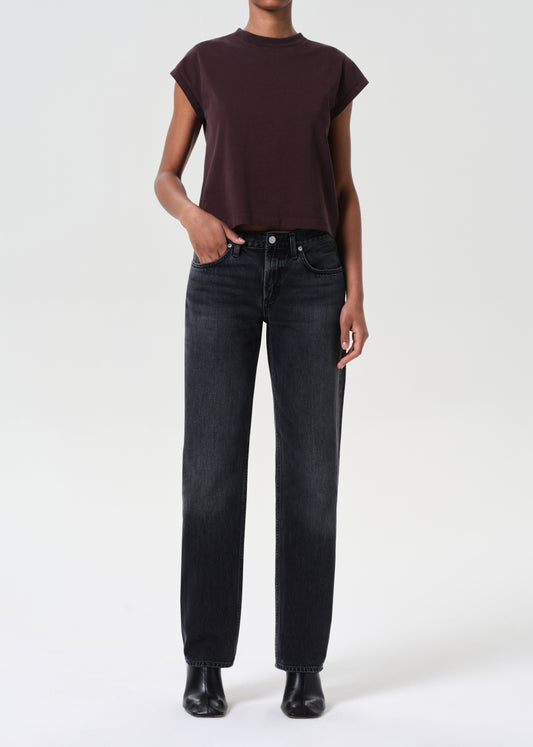 Person wearing a dark brown top and black jeans on a white background