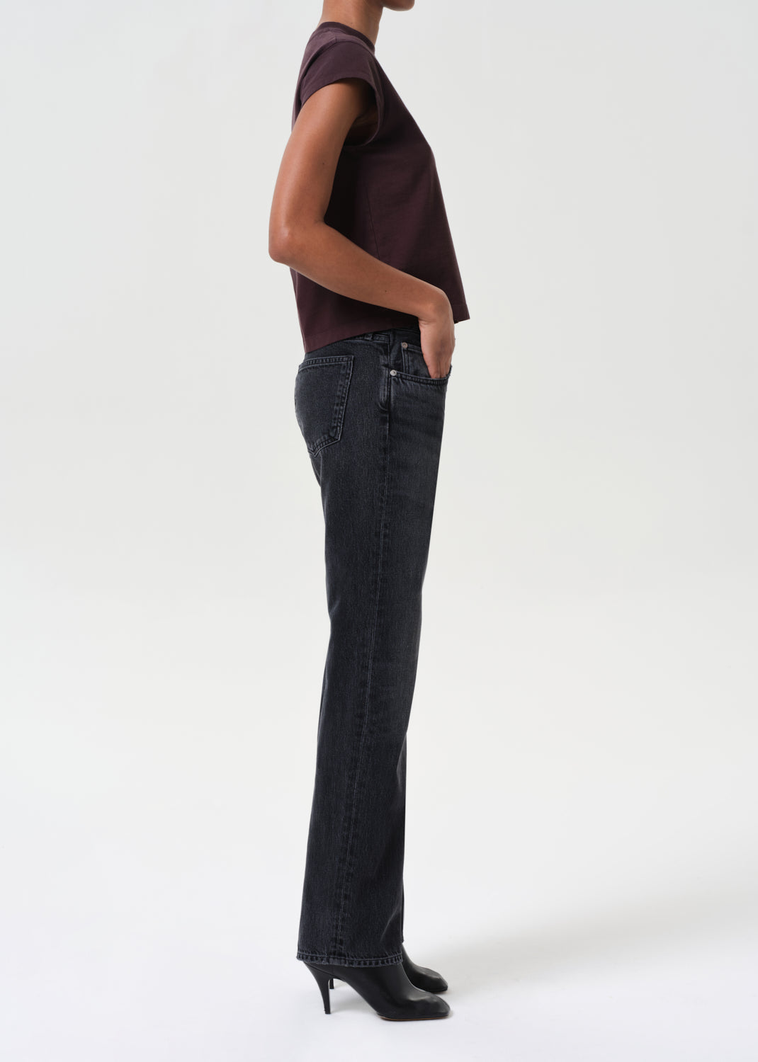 Person wearing a dark top and black jeans on a white background