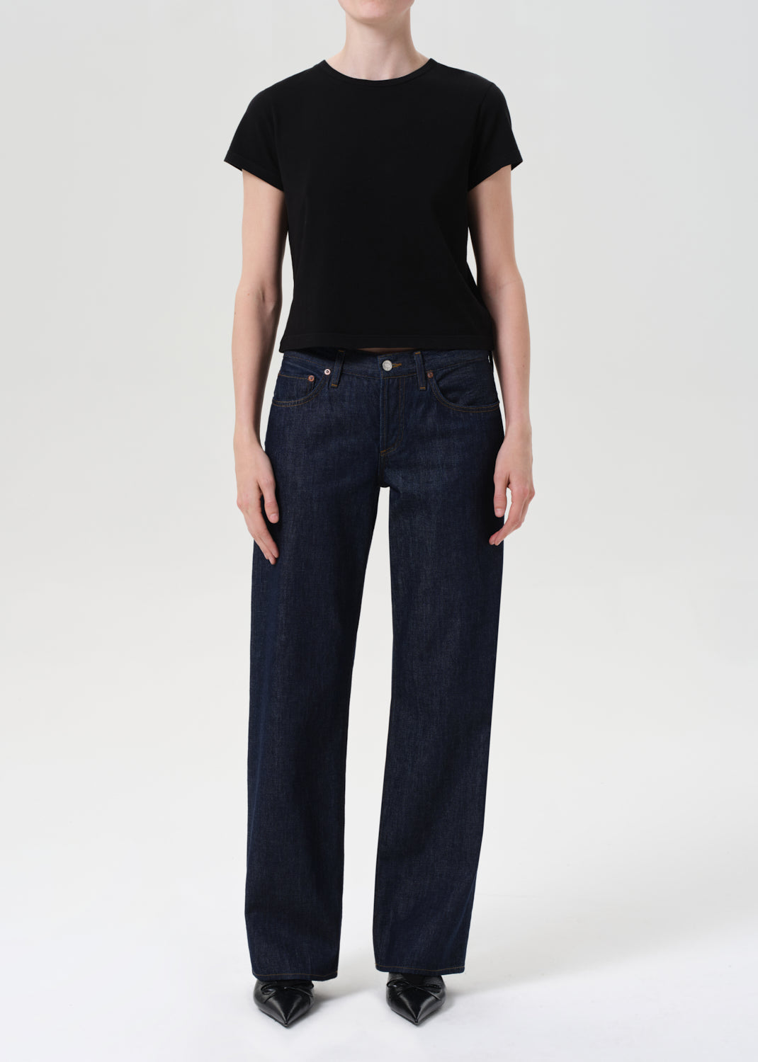 Person wearing a black t-shirt and dark blue jeans on a white background