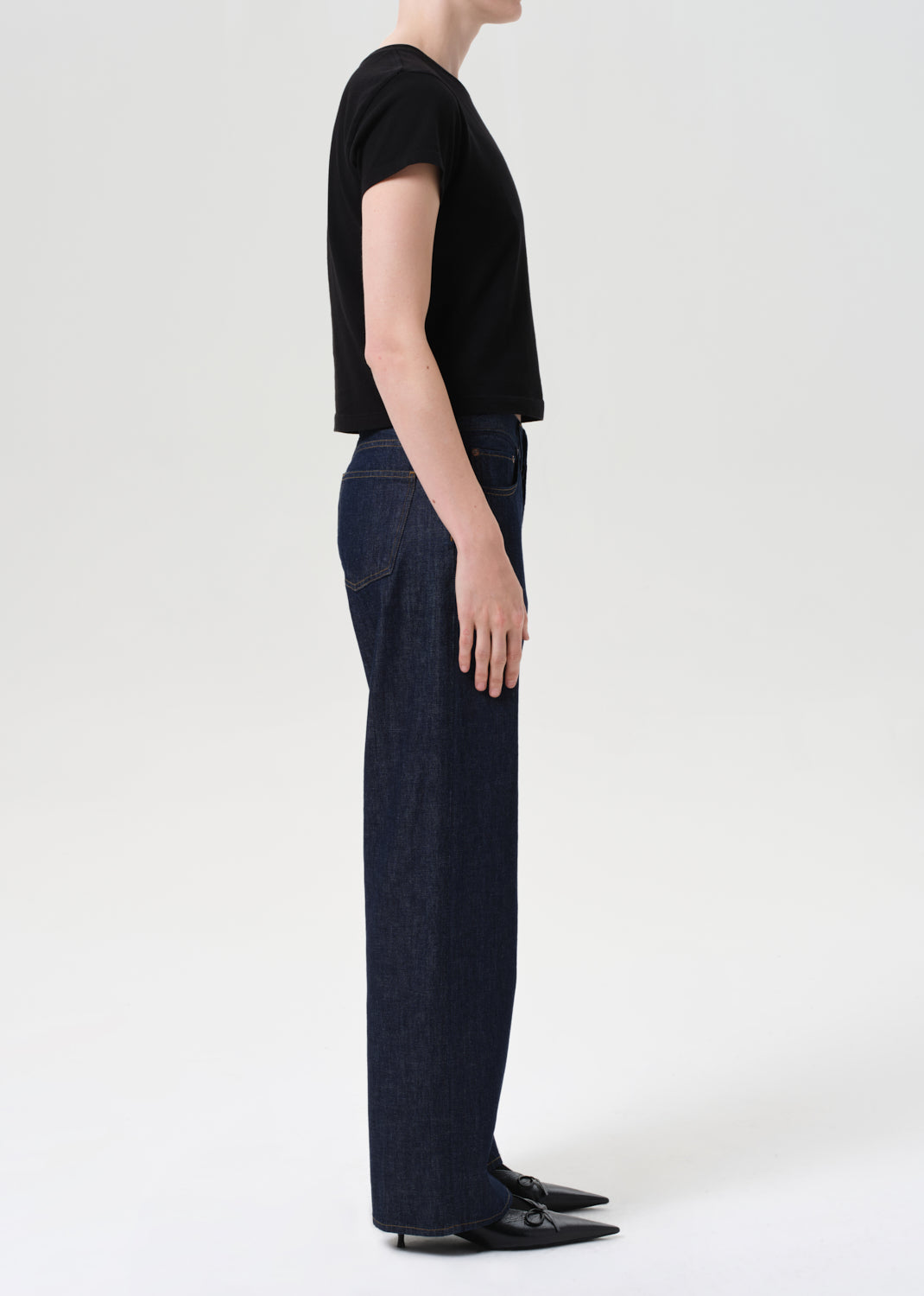 Person wearing a black t-shirt and dark blue jeans on a white background