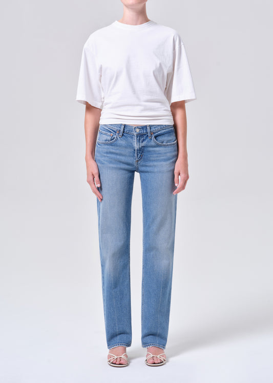 Person wearing a white t-shirt and light blue jeans on a plain background