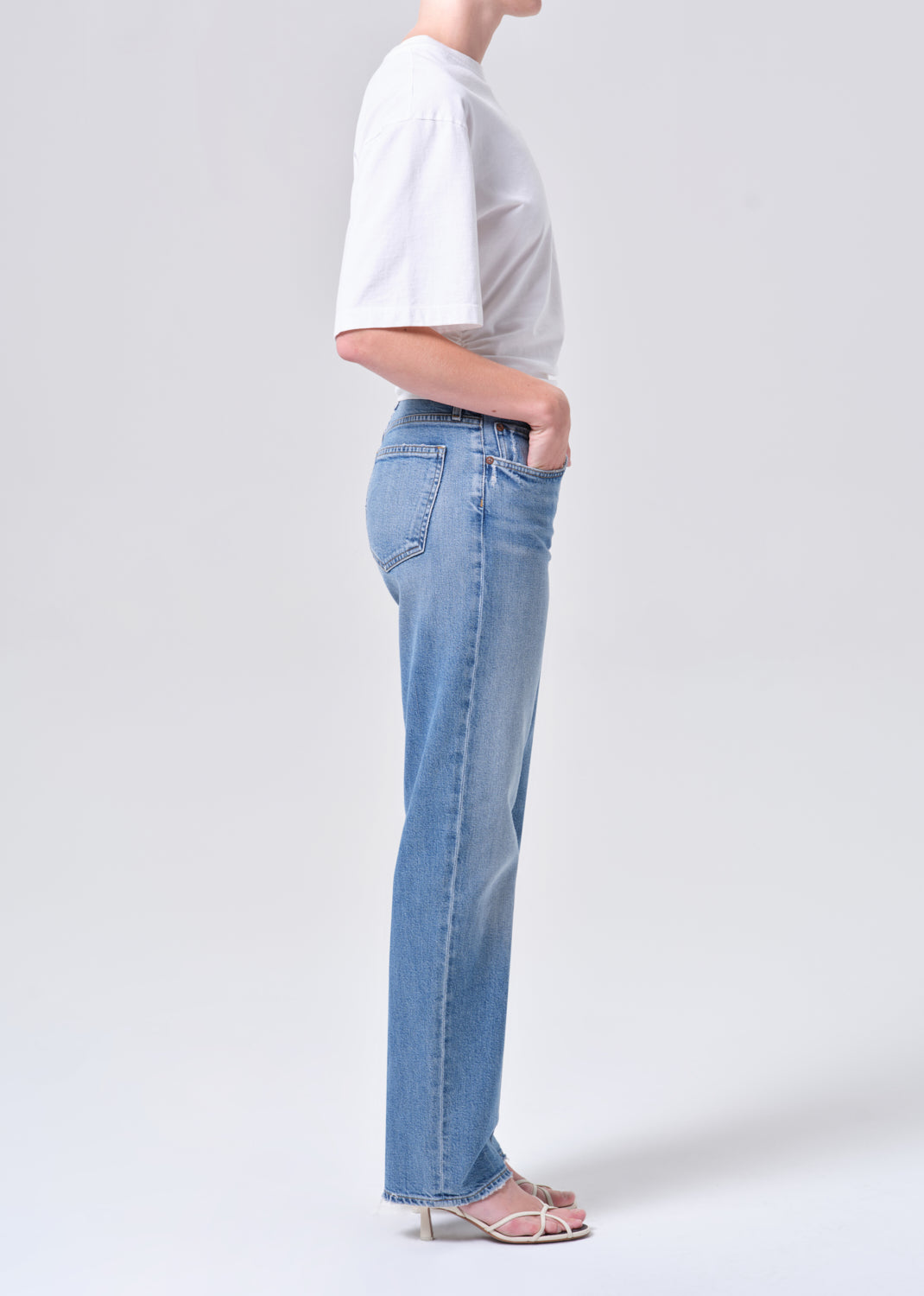 Person wearing light blue jeans and a white shirt on a plain background