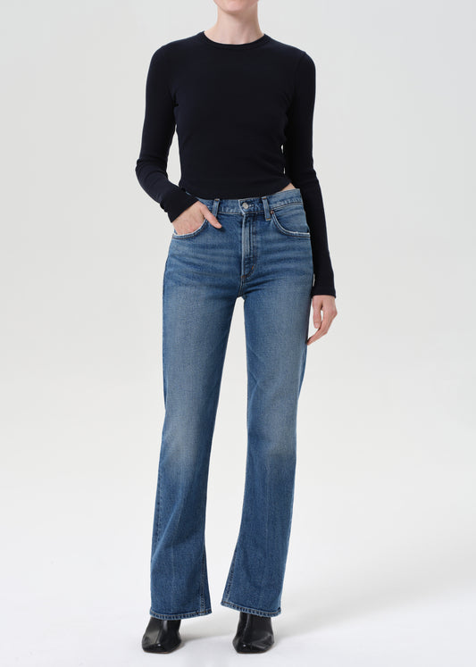 Person wearing a black long-sleeve top and blue jeans on a white background