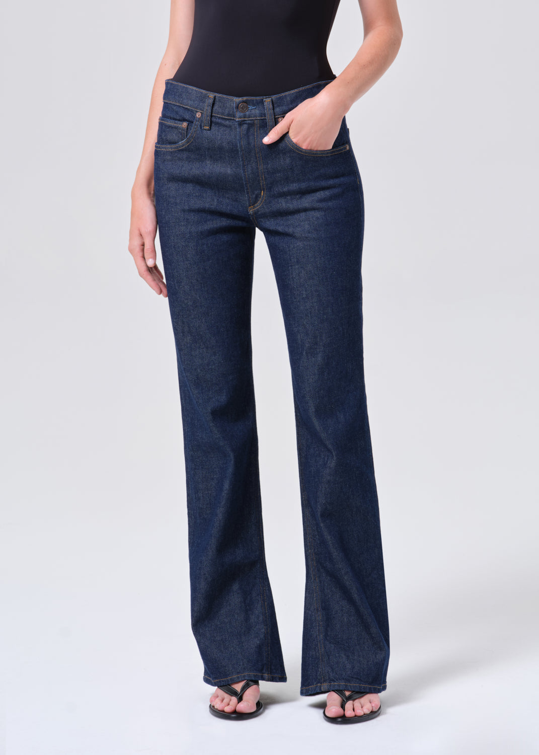 Person wearing dark blue flared jeans on a white background