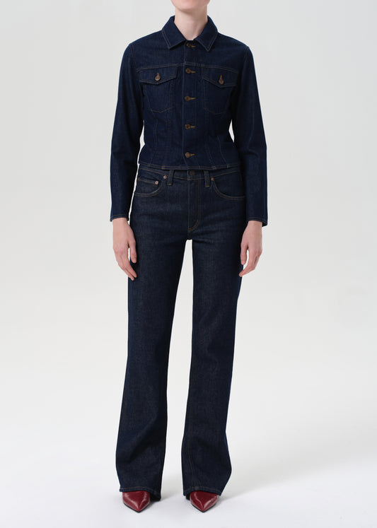 Person wearing a dark blue denim jacket and jeans on a white background