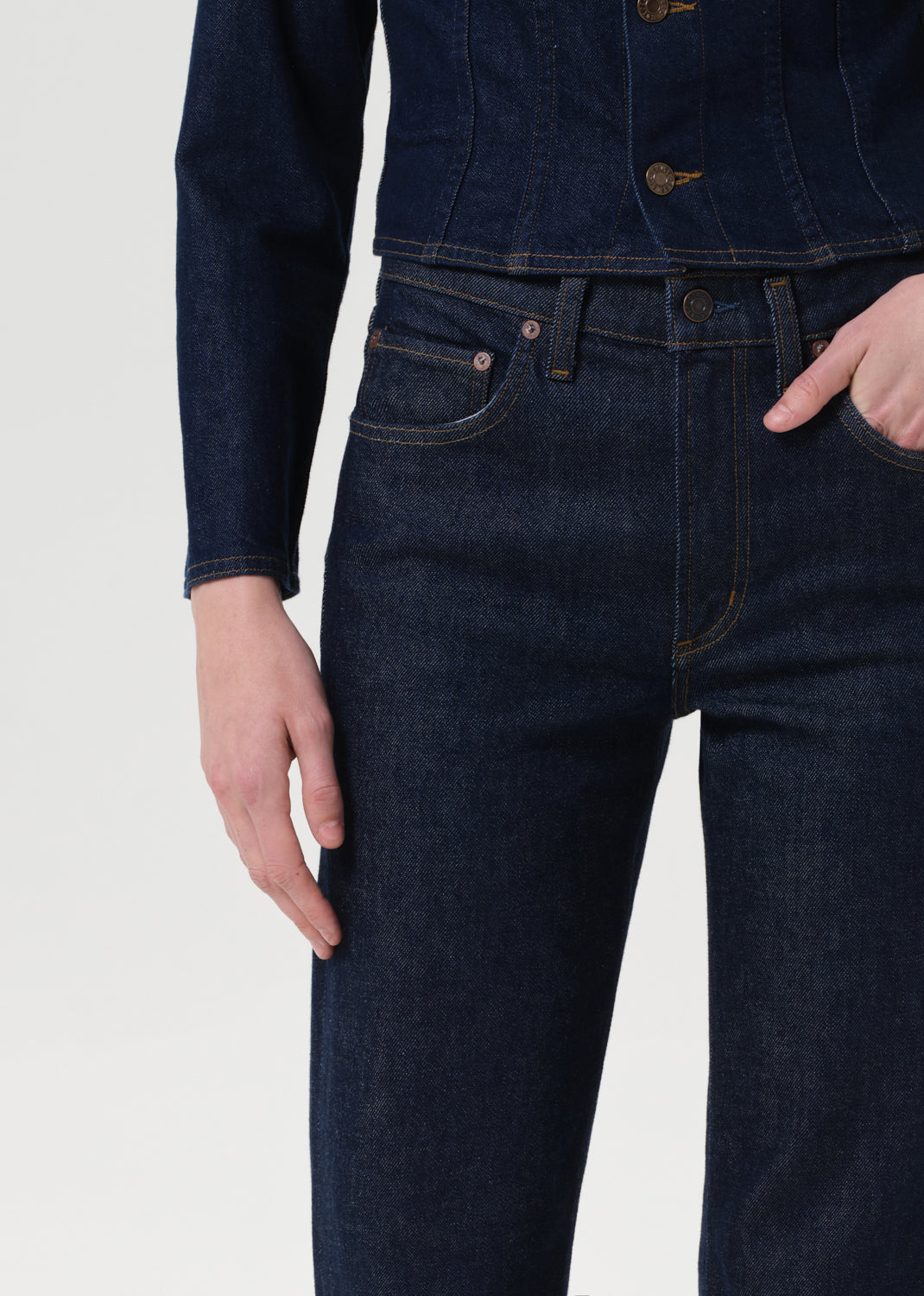 Person wearing dark blue jeans and a matching jacket on a white background