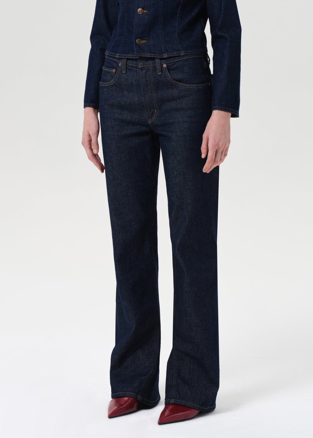 Person wearing dark blue jeans and a matching jacket on a white background