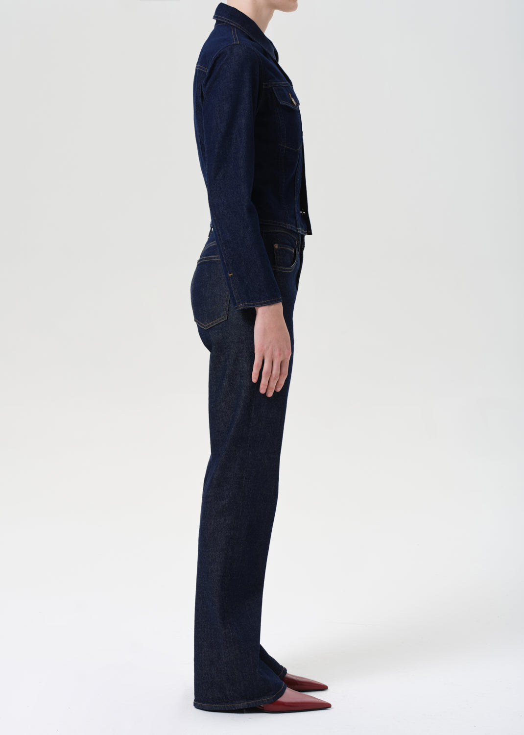 Person wearing a dark blue denim outfit on a white background