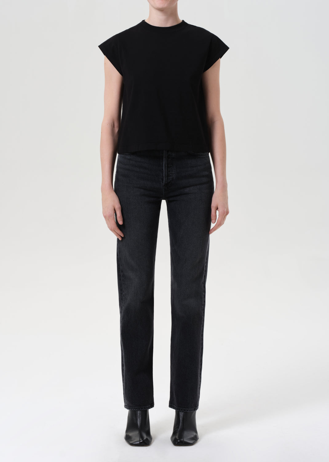 Person wearing a black sleeveless top and black pants on a white background