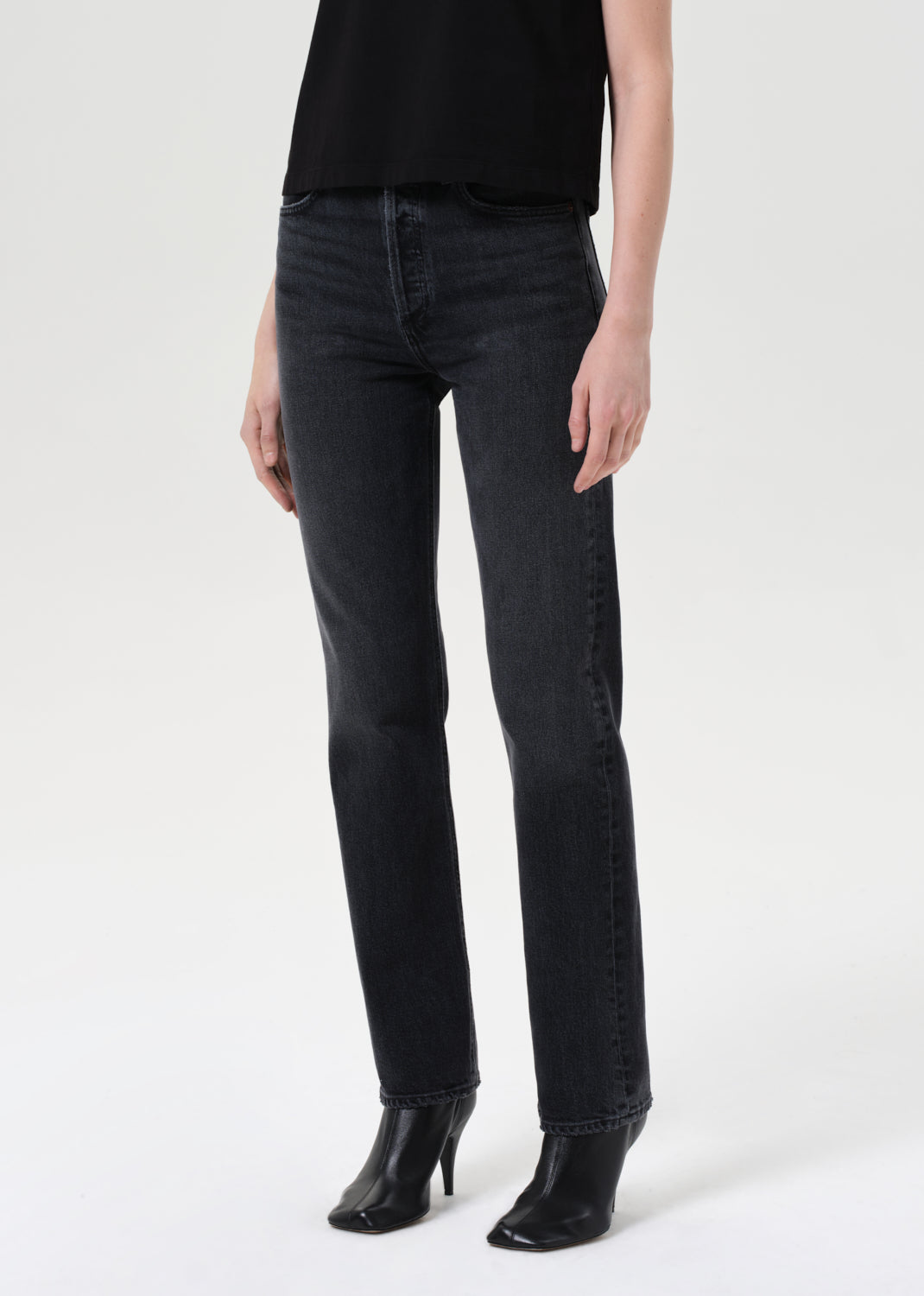 Person wearing black jeans and black shoes on a white background