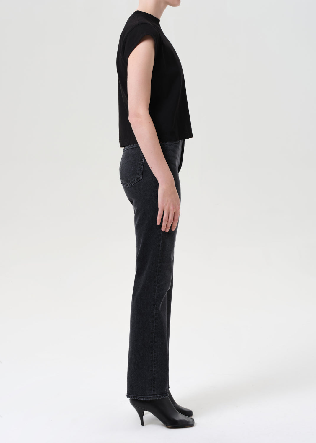 Person wearing a black sleeveless top and black pants on a white background