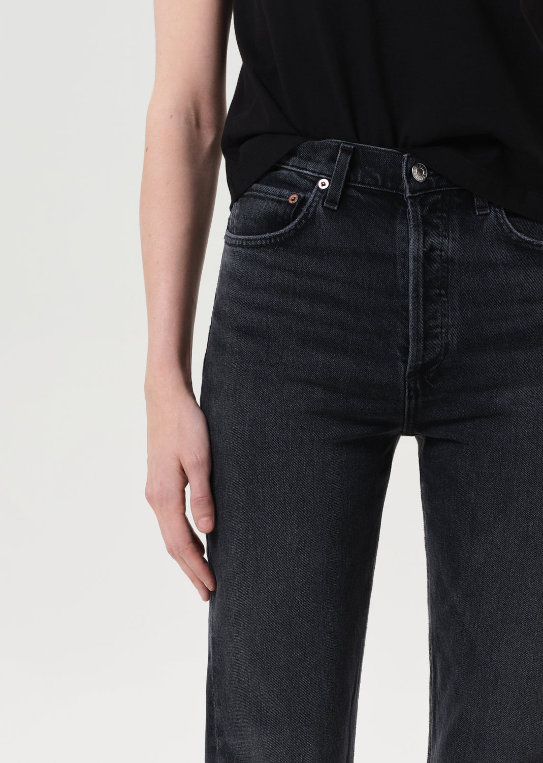Person wearing black jeans and a black top on a light gray background