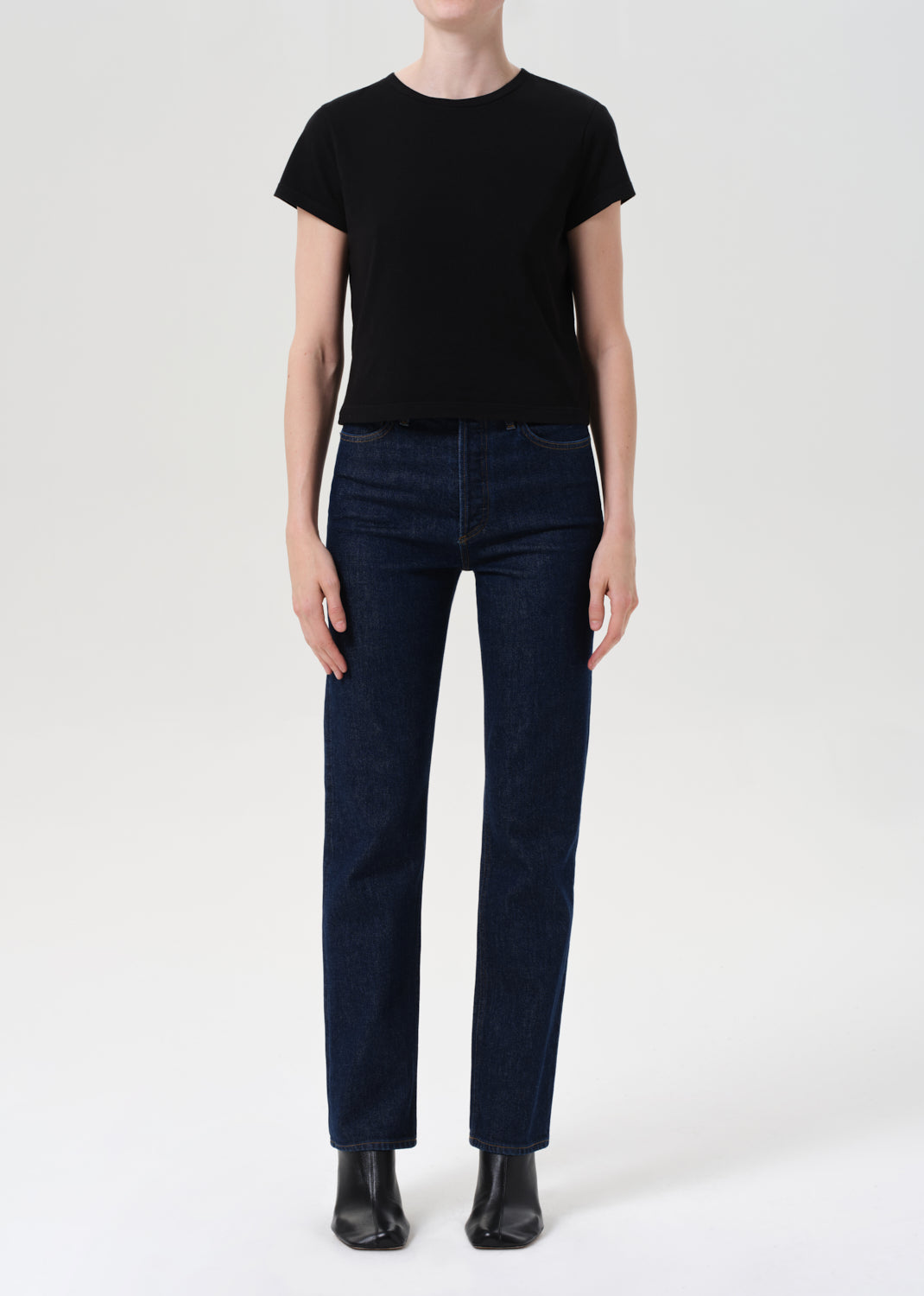 Person wearing a black t-shirt and dark blue jeans on a white background