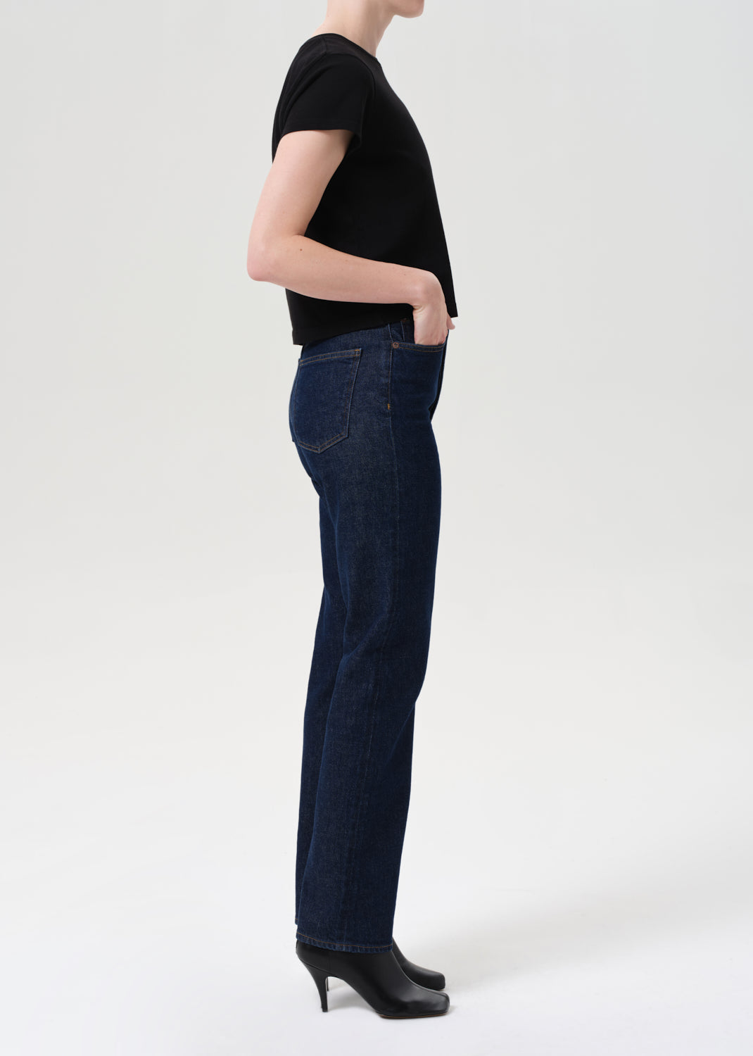 Person wearing dark blue jeans and a black top on a white background