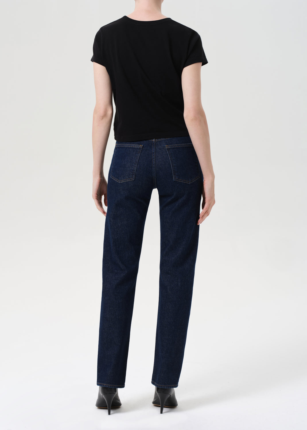 Person wearing a black t-shirt and dark blue jeans on a white background