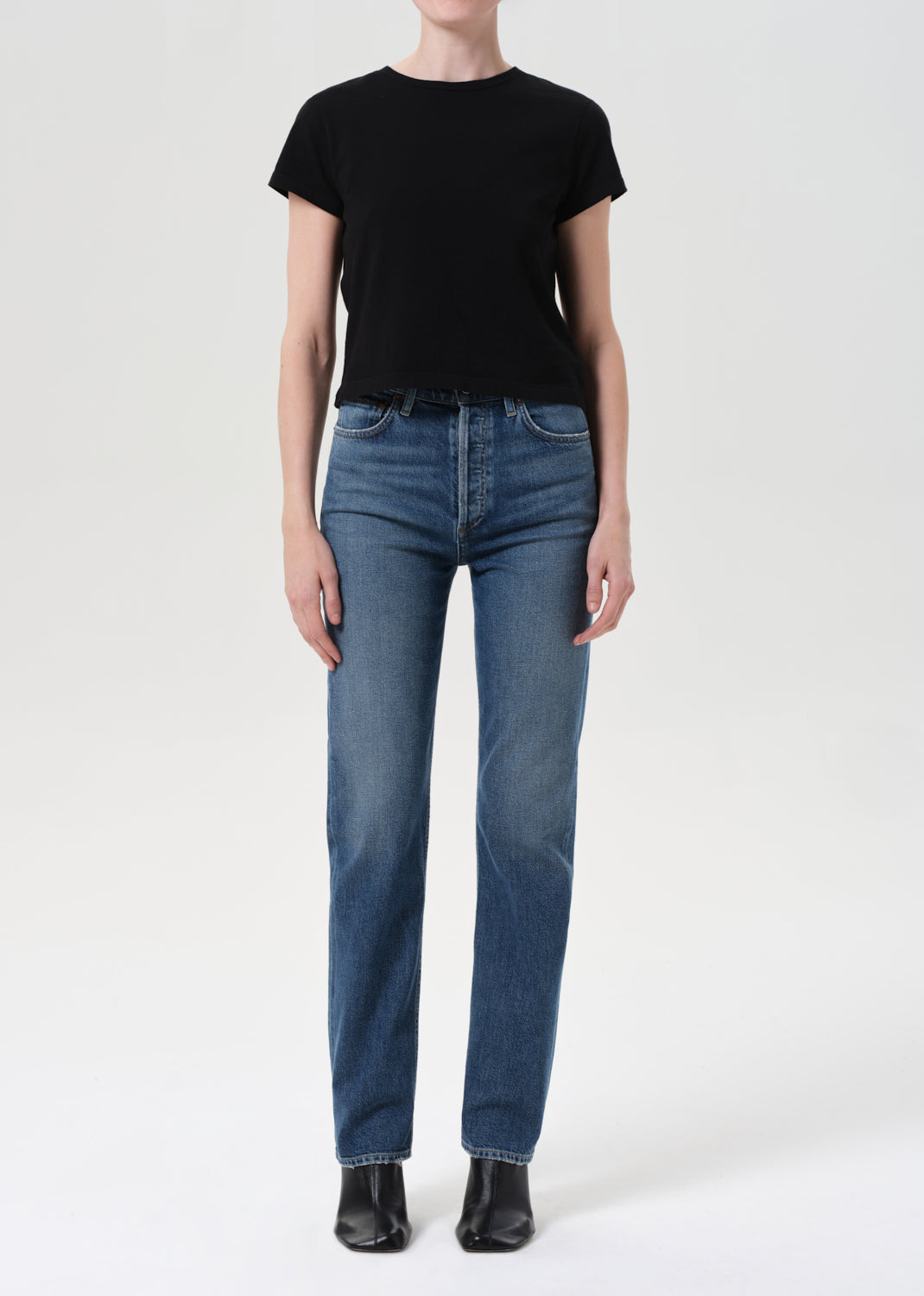 Person wearing a black t-shirt and blue jeans on a white background