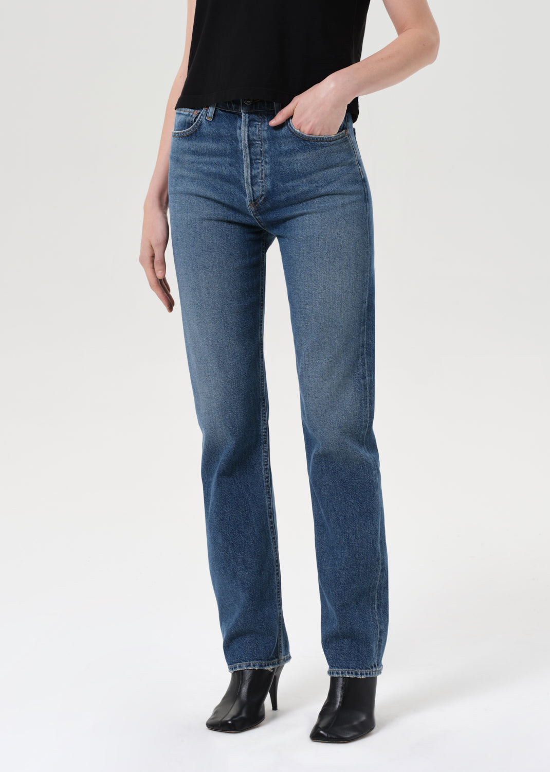 Person wearing blue jeans and black shoes on a white background