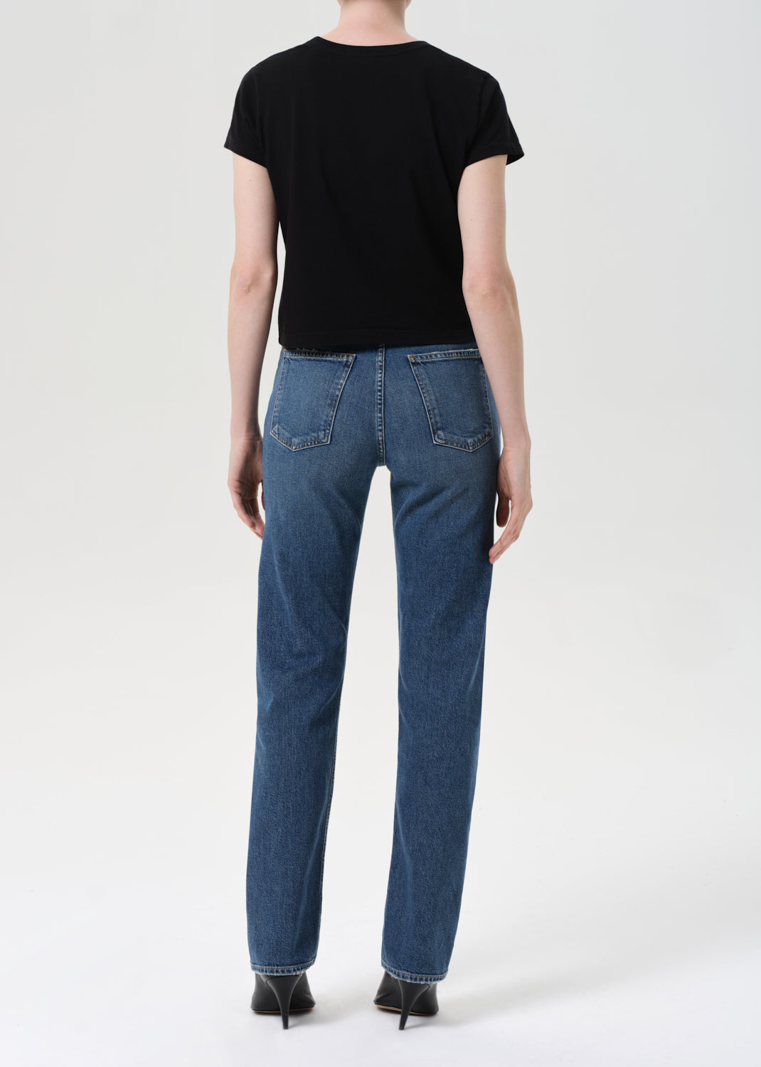 Person wearing a black t-shirt and blue jeans on a white background