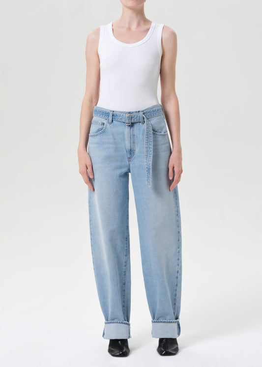 Person wearing light blue jeans and a white tank top on a white background