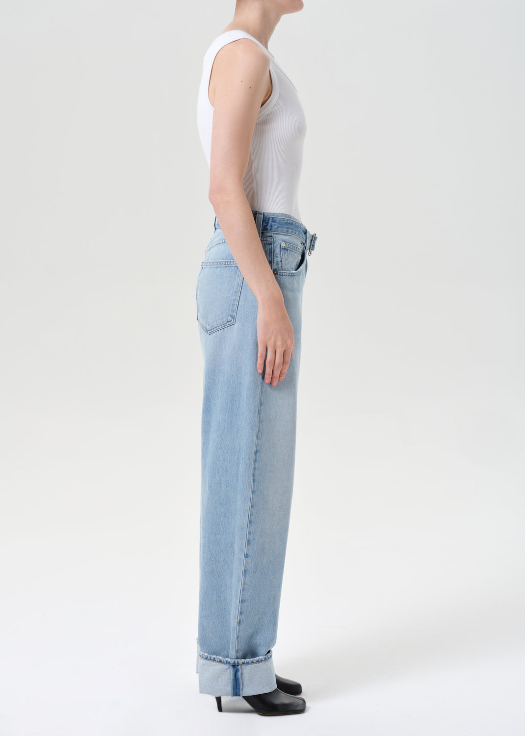 Person wearing light blue jeans and a white top on a white background