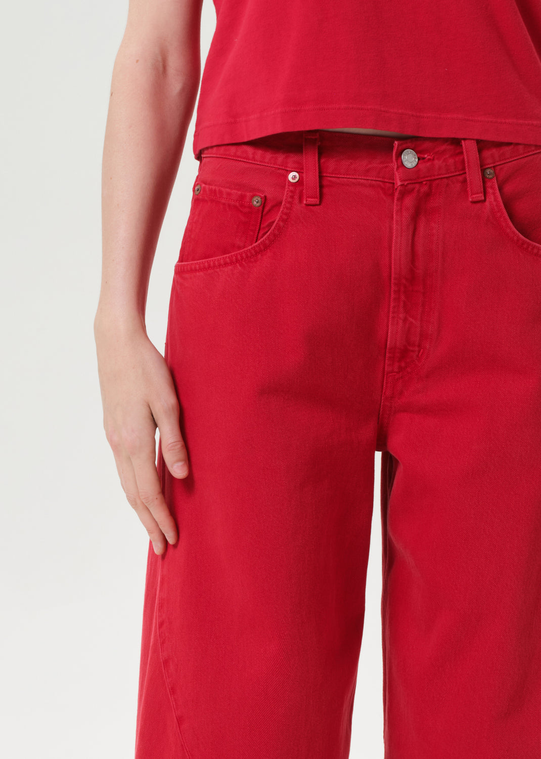 Red jeans worn by a person on a white background