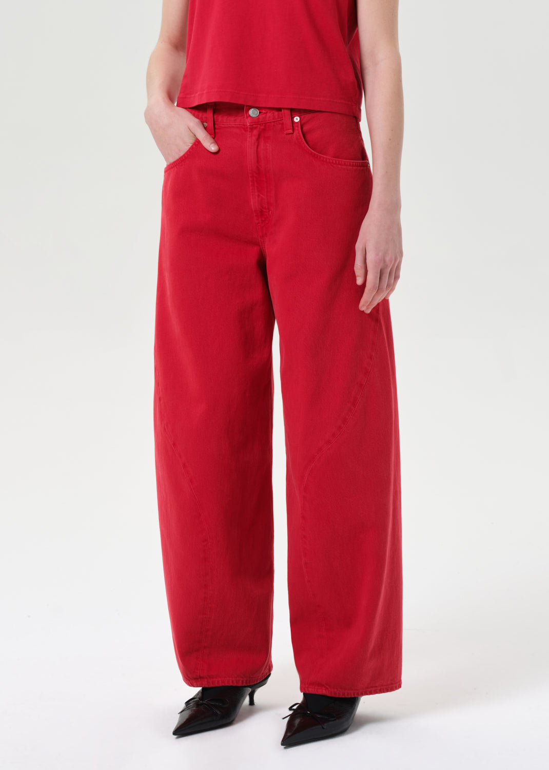 Person wearing red wide-leg jeans and a red top on a white background