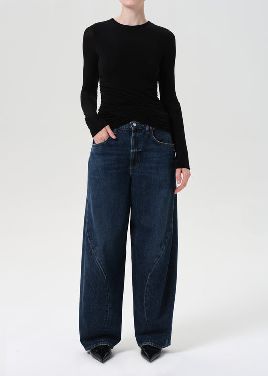 Person wearing a black sweater and dark blue jeans on a white background