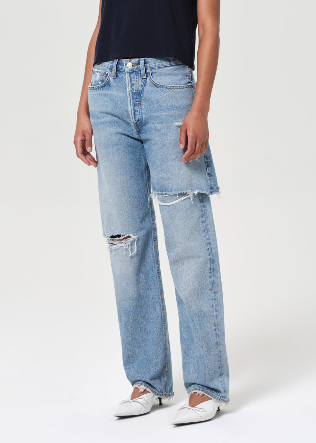 Person wearing light blue jeans with a white background