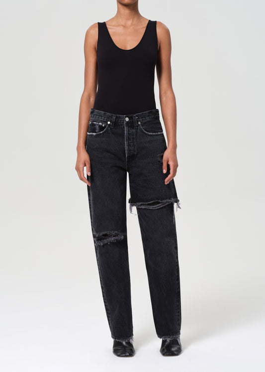 Person wearing a black tank top and black distressed jeans on a white background
