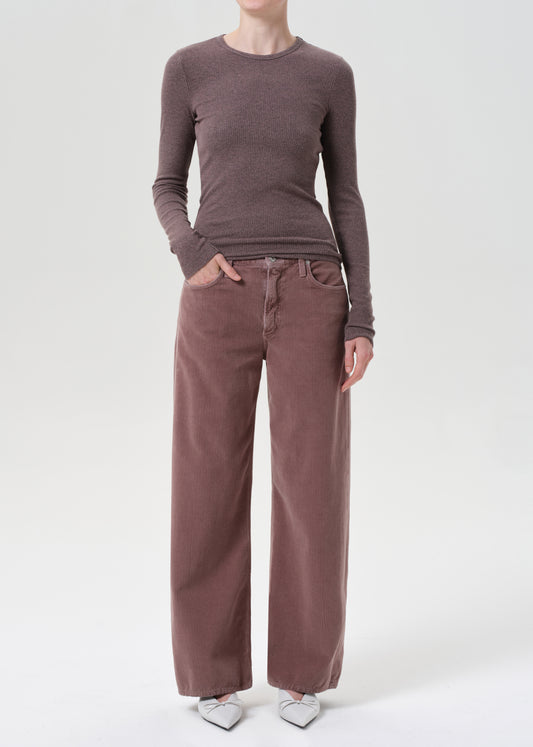 Person wearing a brown long-sleeve top and wide-leg pants on a white background
