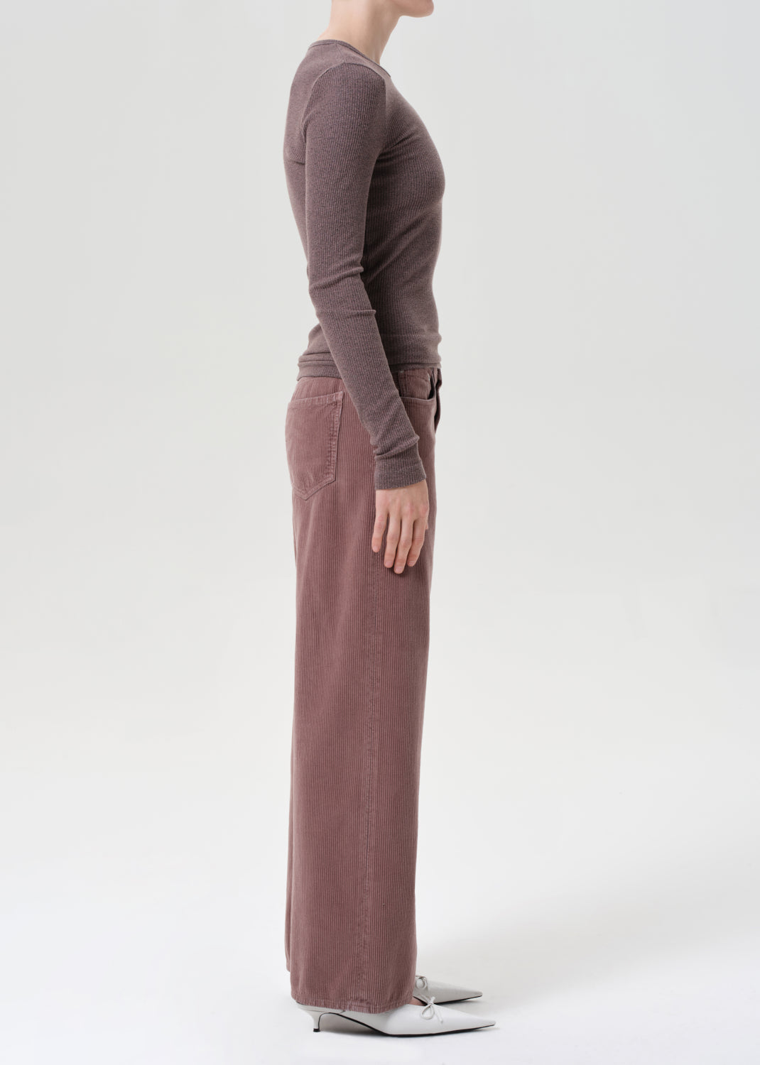 Person wearing a brown long-sleeve top and wide-leg pants on a white background