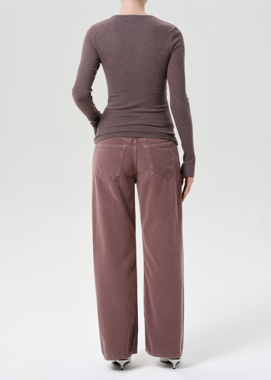 Person wearing a brown long-sleeve top and wide-leg pants on a white background