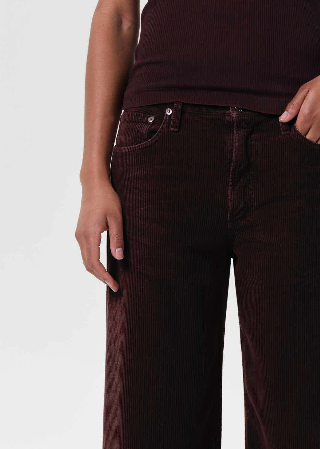 Brown corduroy pants worn by a person on a light gray background