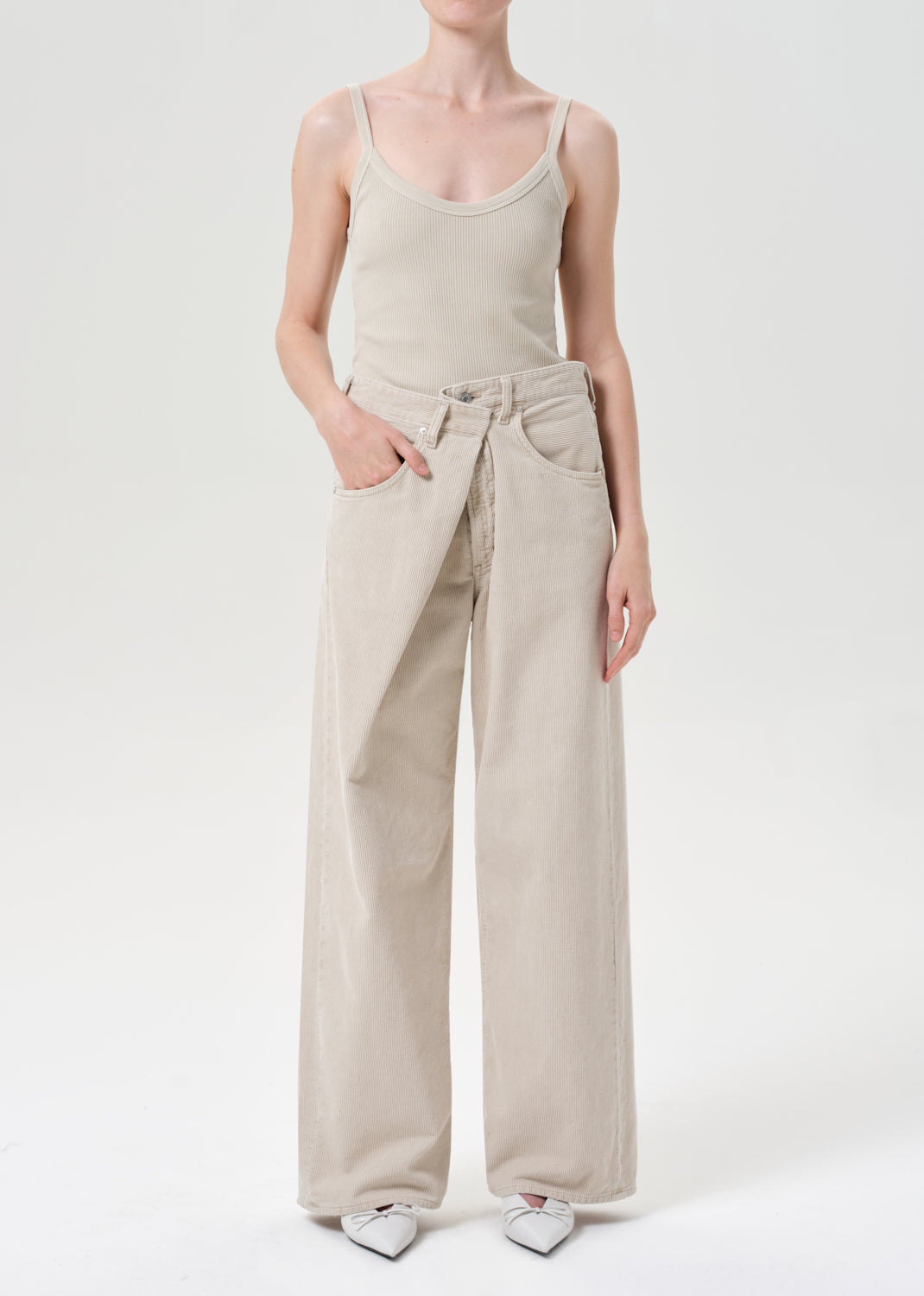 Person wearing a beige tank top and wide-leg pants on a white background